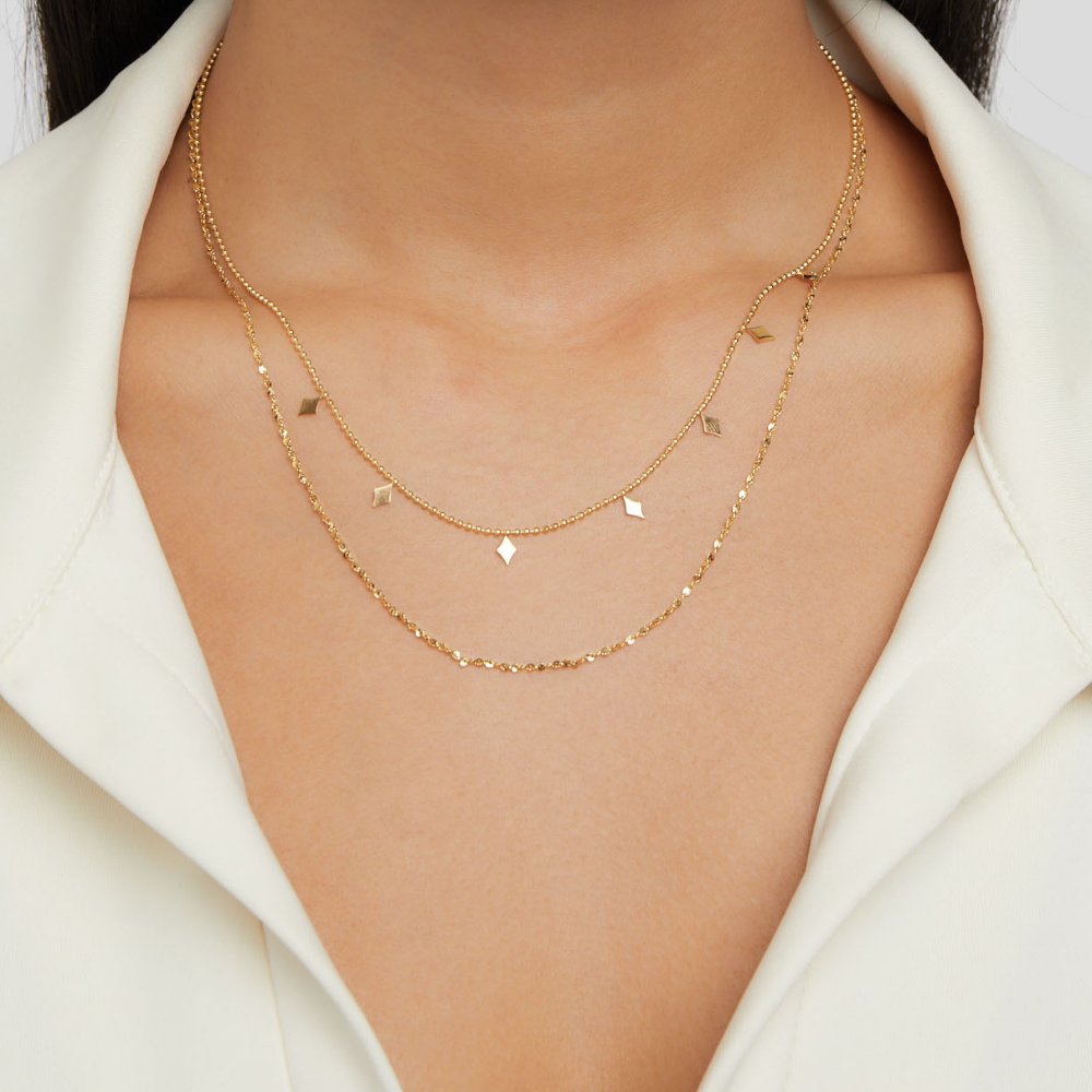 Phoenix Layered Necklace, worn layered at the neck over a white collared top, gold diamond charms