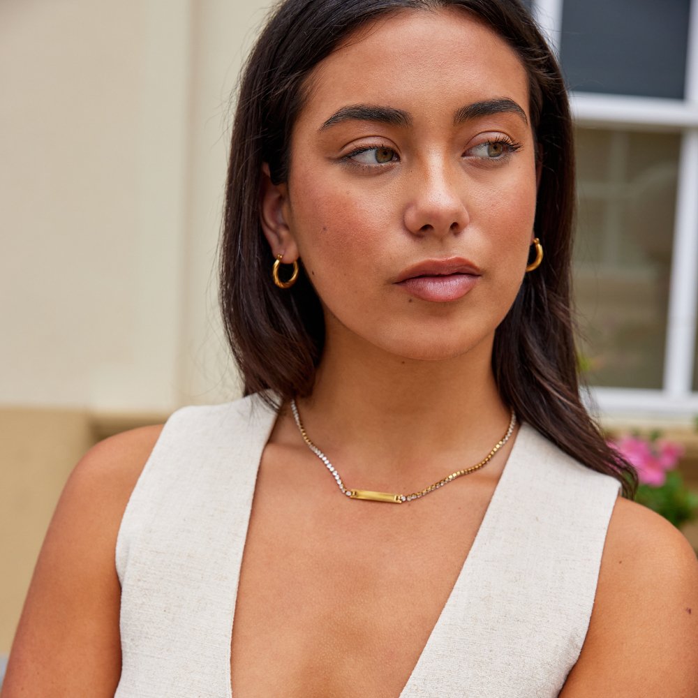 Rina Crystal Necklace, worn on a model in a cream sleeveless top, with gold hoop earrings