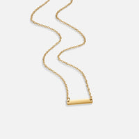 Rina Gold Bar Necklace, gold chain necklace laid out on white with a polished bar pendant