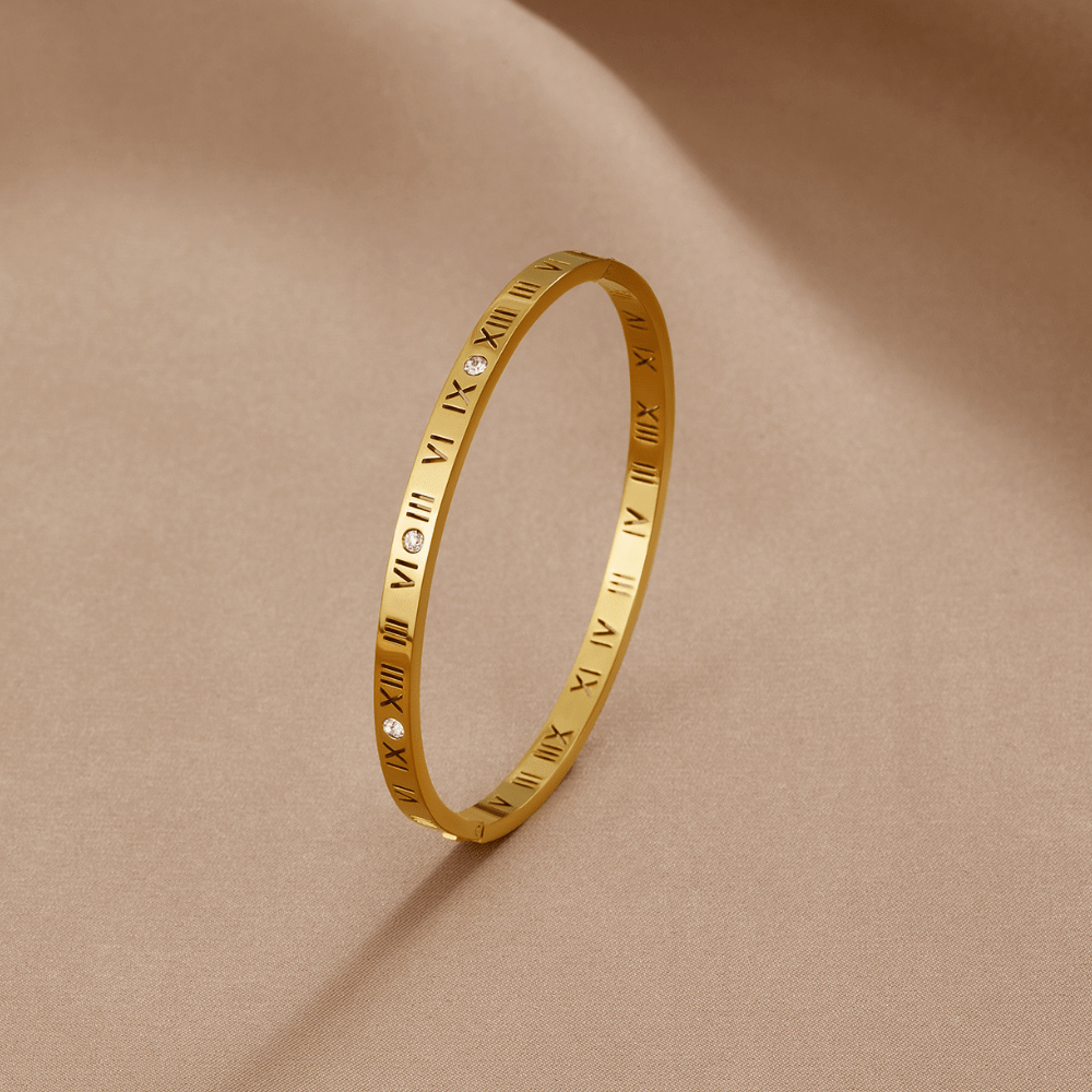 Roman 18K Gold Bangle, gold bangle with Roman numerals and small stones, on a beige satin cloth