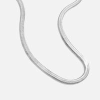 Sarya Snake Chain Silver Necklace, flat-lay close-up of a silver herringbone chain curving on
