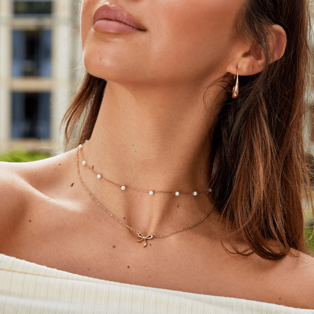 Serenity Bow Pendant Necklace, worn on a neck with a pearl chain and bow pendant