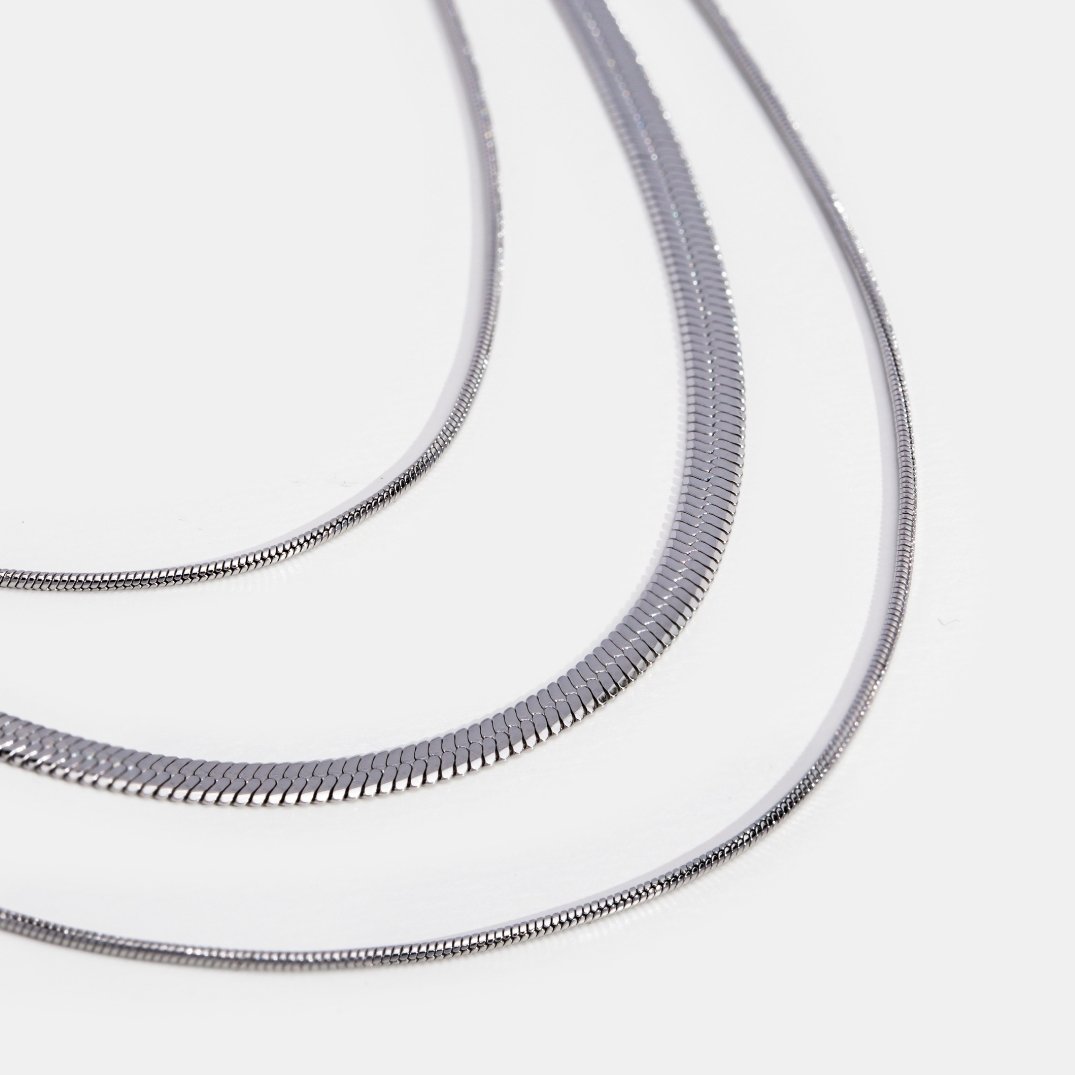 Silver Multi-Layered Chain Necklace, three silver chains of different widths on a white