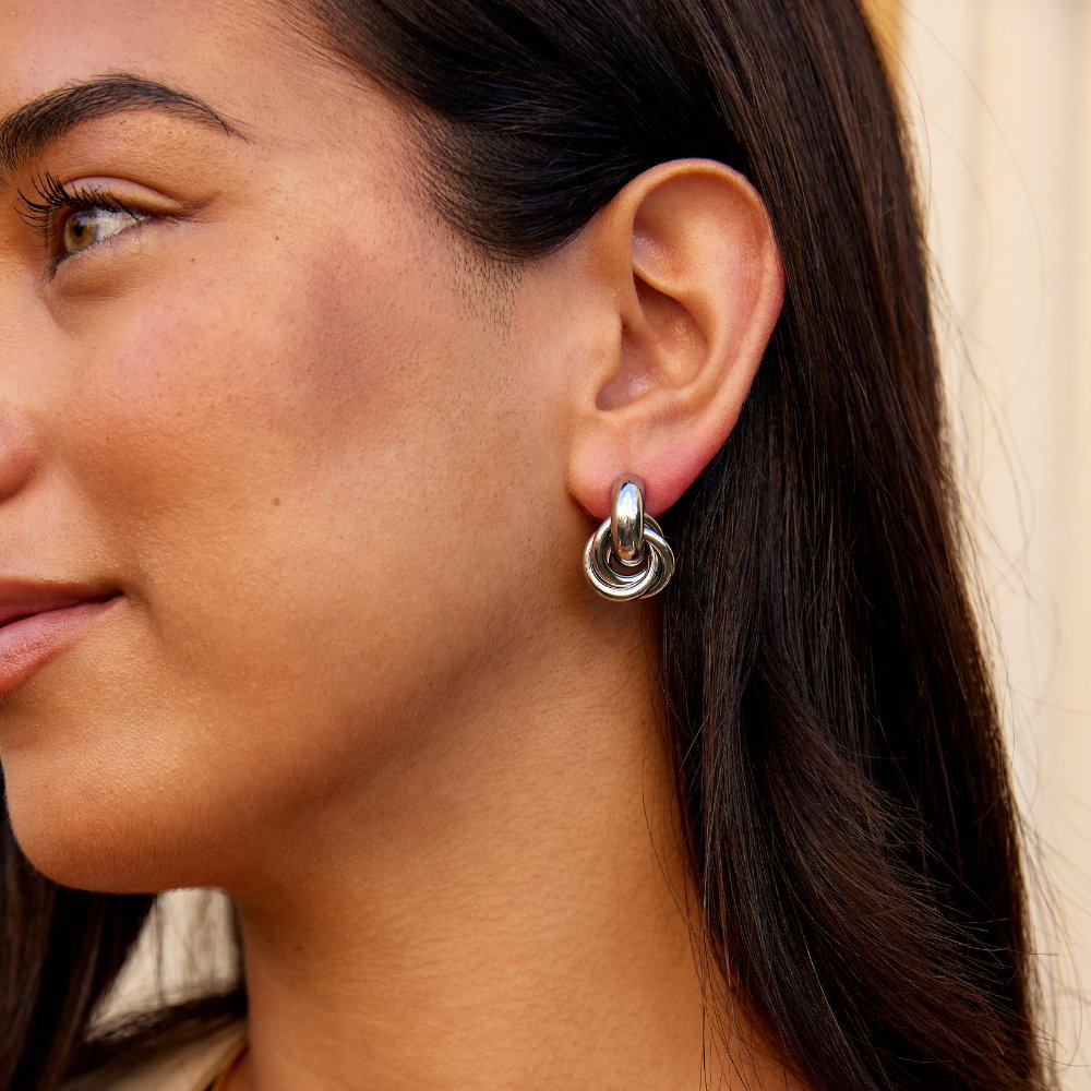 Sofia Twisted Silver Hoop Earrings, worn on an ear, silver knot drop below a small hoop