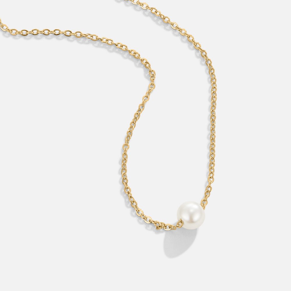 Solitaire Gold Pearl Necklace, gold chain necklace laid on white with a single white pearl