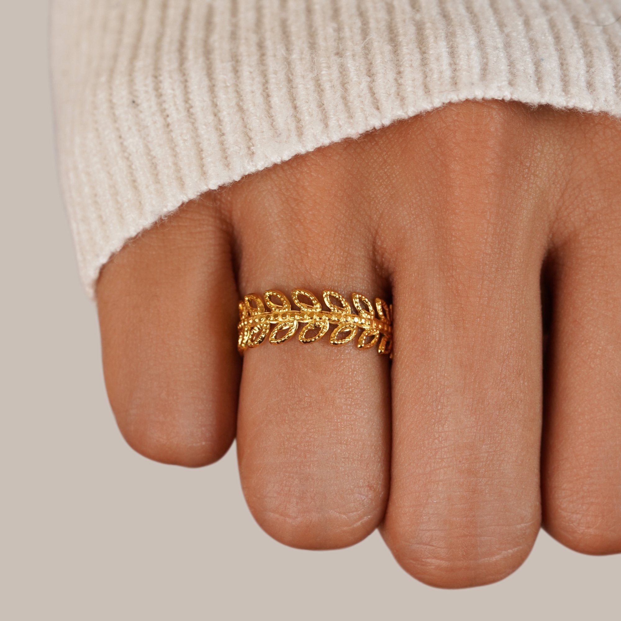 Summer Bloom Leaf Ring, worn on a finger with a cream knit sleeve, close-up