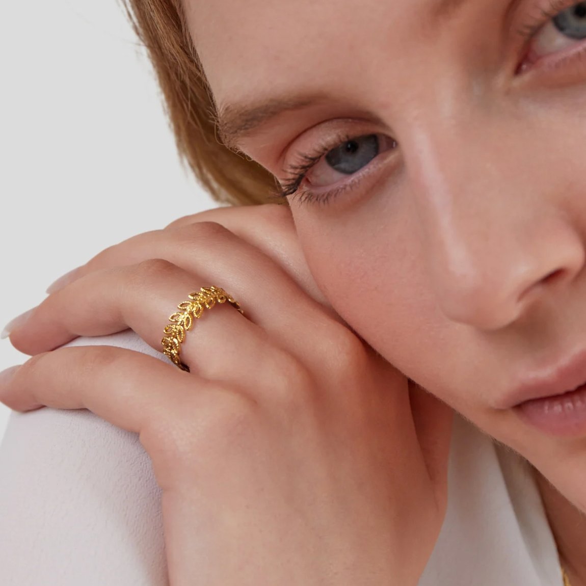 Summer Bloom Leaf Ring, worn on a hand resting against a cheek, gold openwork band