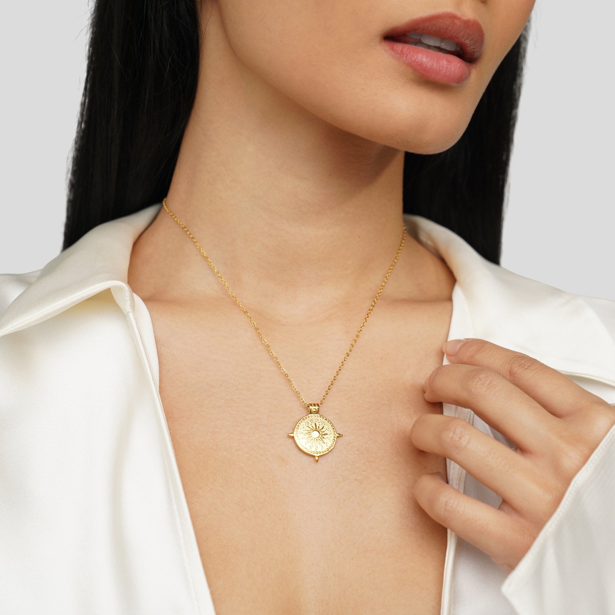 Summer Solstice Gold Necklace, worn on a neck with a white satin shirt, round sunburst pendant