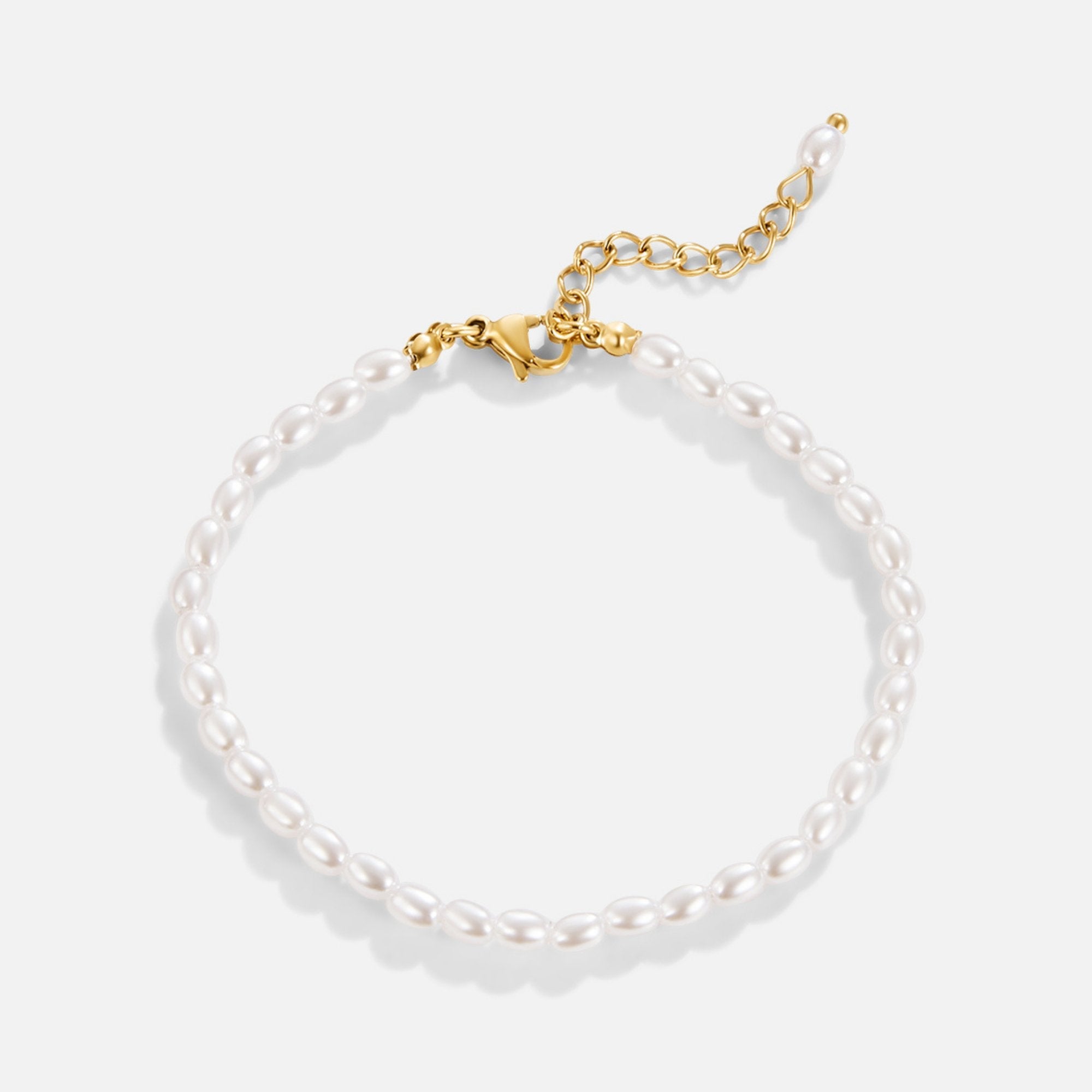 Temi Pearl Bracelet, flat lay of white oval pearls with gold clasp and extender chain