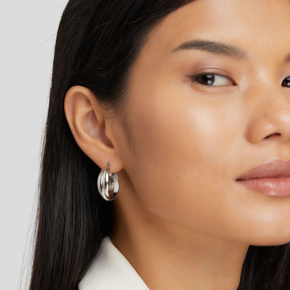 Talia Silver Hoop Earrings, worn on an ear by a model with long dark hair