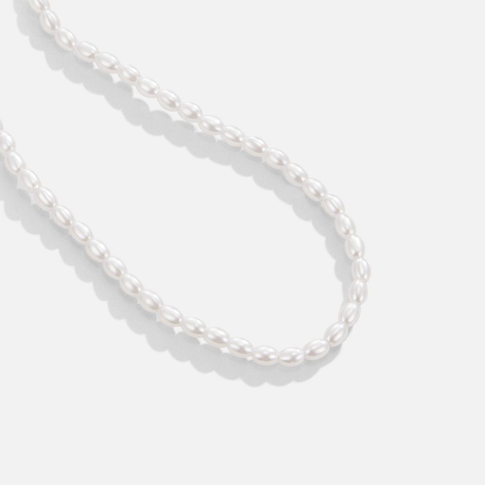 Temi Pearl Necklace, close-up of white oval pearls strung in a curve on white