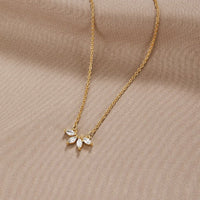 Tiffany Crystal Leaf Pendant Necklace, laid flat on beige fabric, gold chain with five pointed