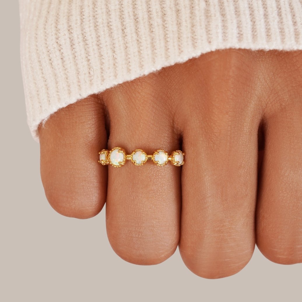 Tiffany Opal Stone Ring, worn on a finger with a cream knit sleeve, close-up, gold band