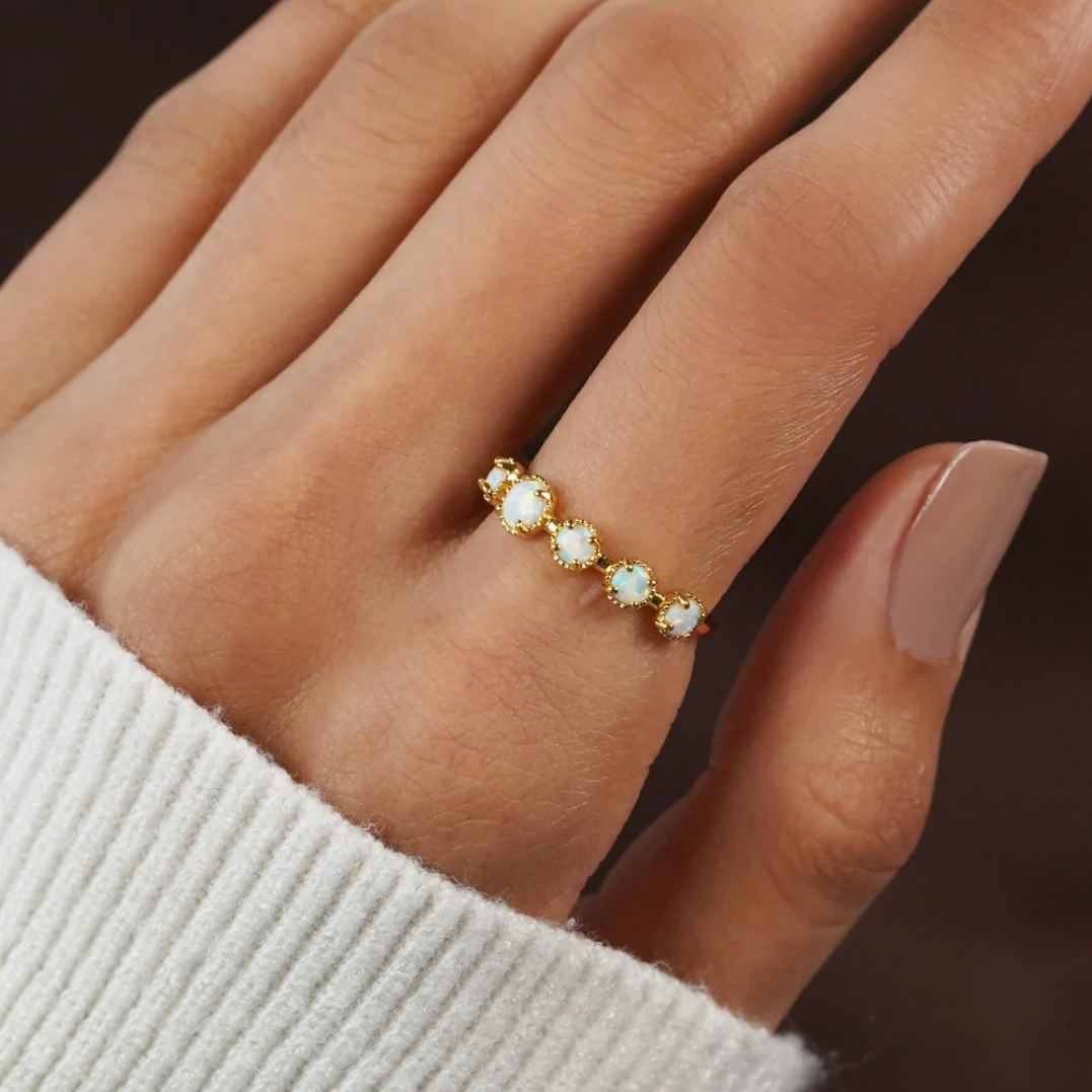 Tiffany Opal Stone Ring, worn on a hand with a white knit sleeve, gold band with opals