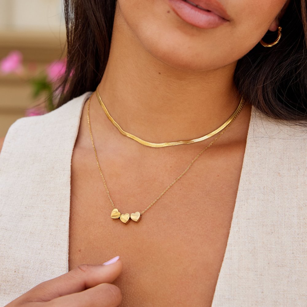 Trio Heart Pendant Necklace, worn on a neck with a gold snake chain layered above