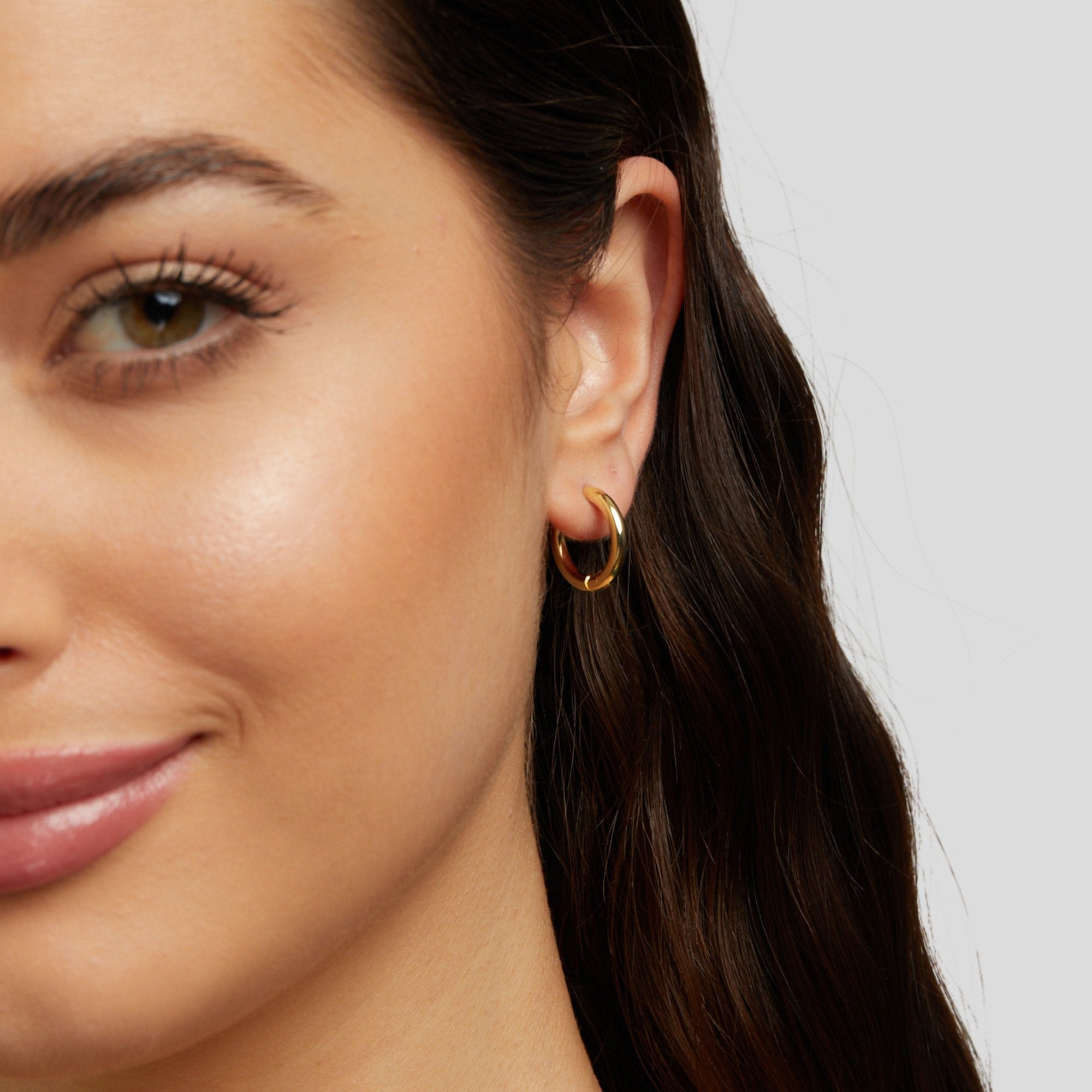 Triple Hoop Earrings Set, worn in an ear on a woman with long dark hair, polished gold hoop