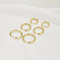 Triple Hoop Earrings Set, six gold hoop earrings in three sizes on white fabric