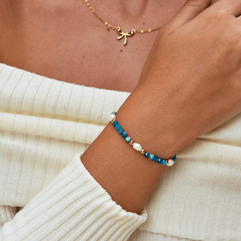 Turquoise Blue & Pearl Bead Bracelet, worn on a wrist with a gold pendant necklace and cream