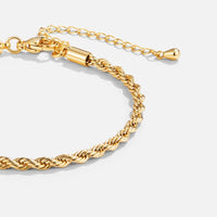 Twisted 18K Gold Bracelet, close-up of a gold rope-twist bracelet on a light grey background