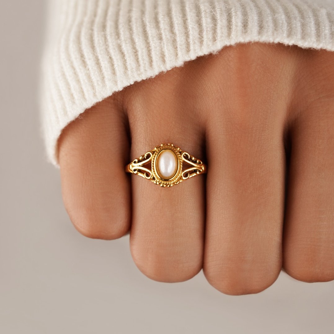 Vintage Royal Pearl Ring, worn on a finger in a cream knit sleeve, gold with a pearl