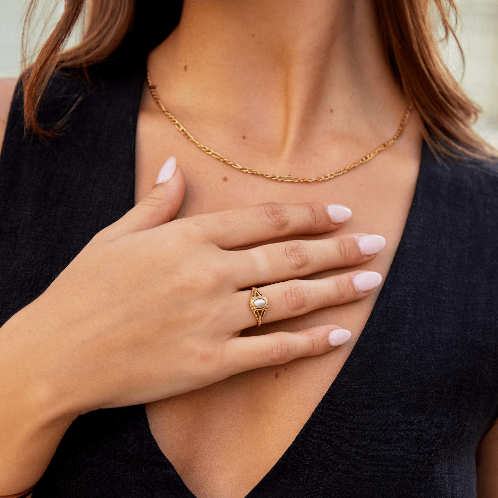 Vintage Royal Pearl Ring, worn on a hand over a chest, with a gold chain necklace
