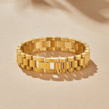 Watch Chain Bracelet, lying flat on sand-coloured surface in sunlight, polished gold links
